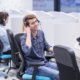 A young person smiling while on the phone at a help desk job.