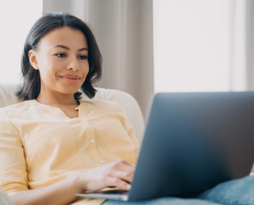 Smiling woman using a laptop in her home.