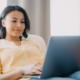 Smiling woman using a laptop in her home.