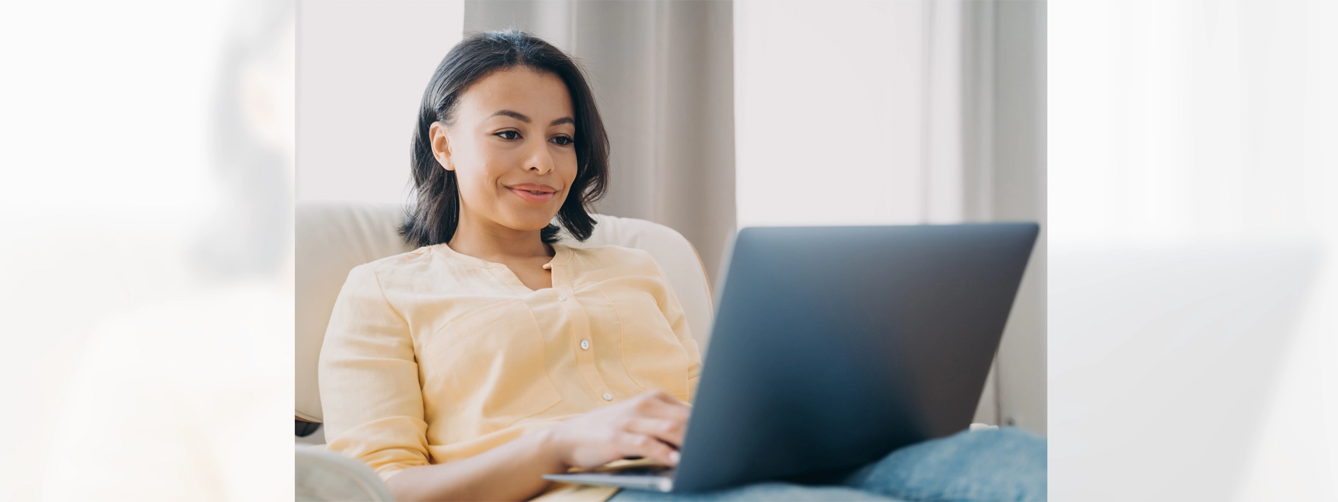 Smiling woman using a laptop in her home.