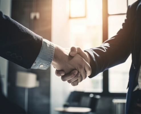 Two men wearing suits shake hands.
