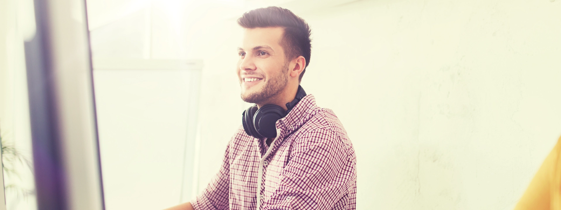 careerAdvancement A smiling man wearing headphones sits at a computer, taking notes.